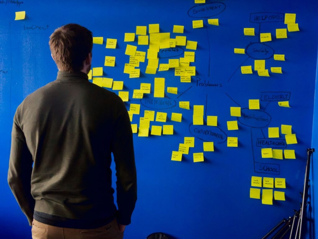 Person analyzes mind map of sticky notes on board.