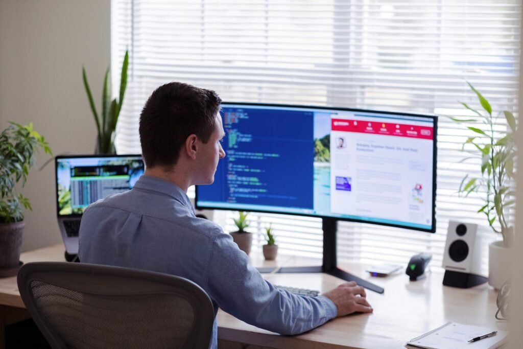 Person working on dual monitors coding and reading