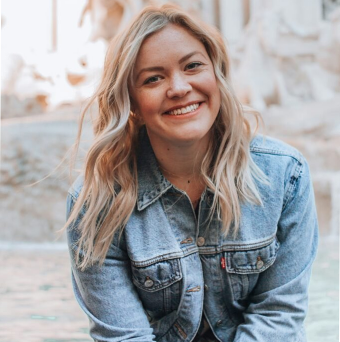 Smiling woman in denim jacket outdoors.