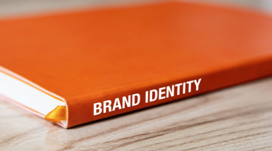 Orange book titled Brand Identity on wooden surface.