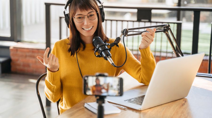 Woman podcasting with microphone and laptop.