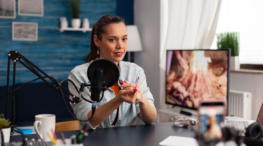 Woman podcasting with microphone in home studio.