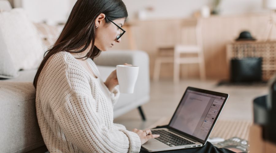 Woman working on laptop, drinking coffee