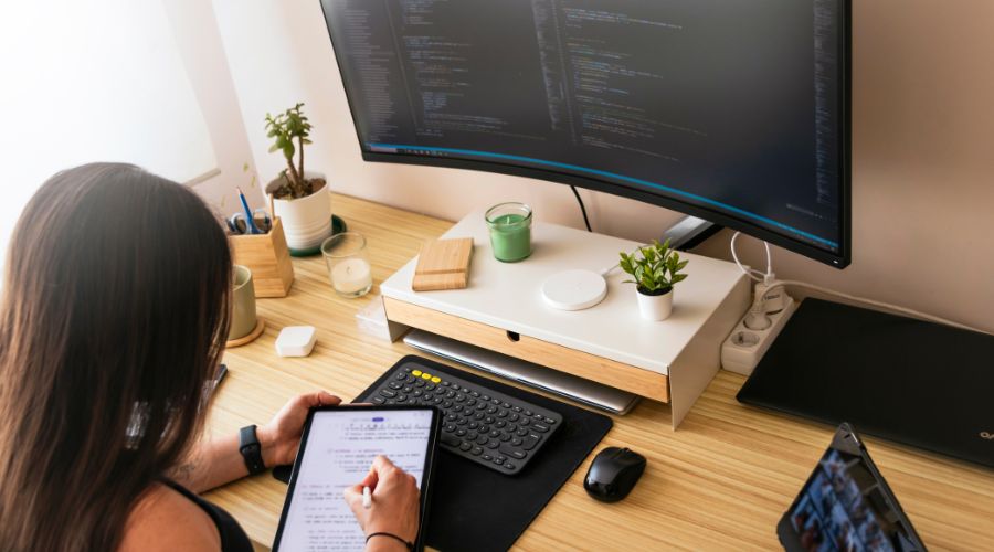 Person working with tablet and computer monitor.