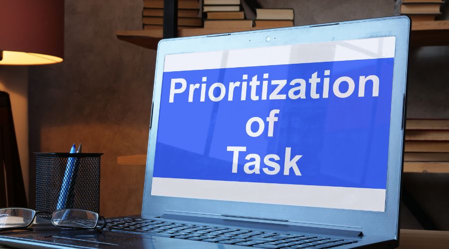 Laptop screen displaying 'Prioritization of Tasks' message.