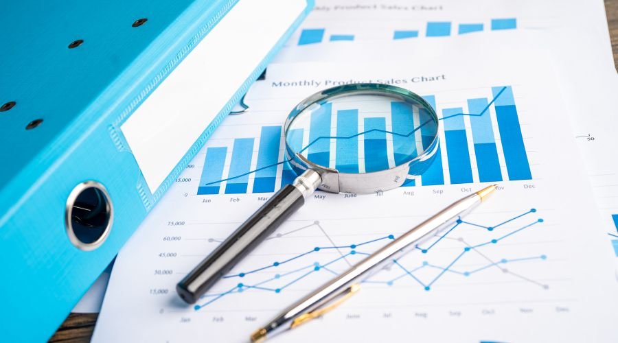 Sales charts with magnifying glass and pen displayed.