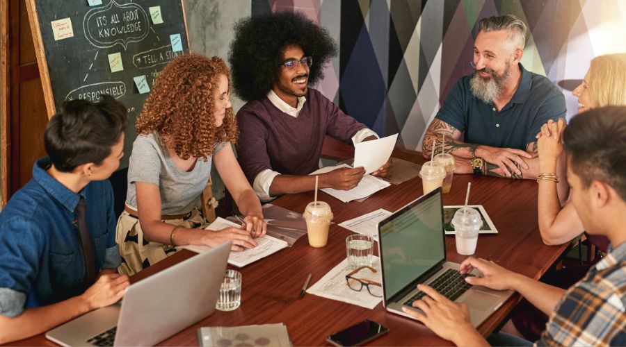 Diverse team having a meeting with laptops and drinks.