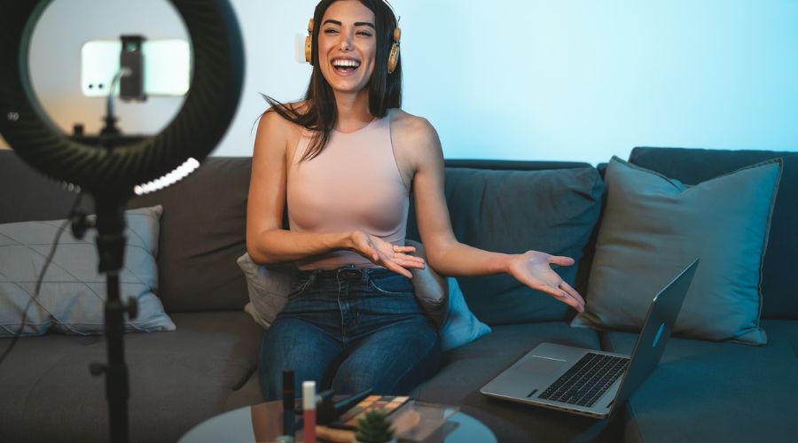 Woman podcasting with headphones and laptop at home.