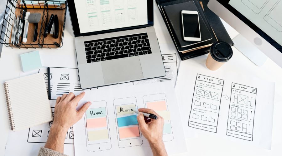 Person designing mobile app wireframes on desk