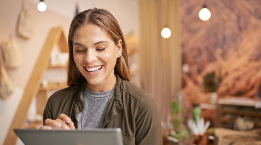 Woman smiling while using a tablet indoors.