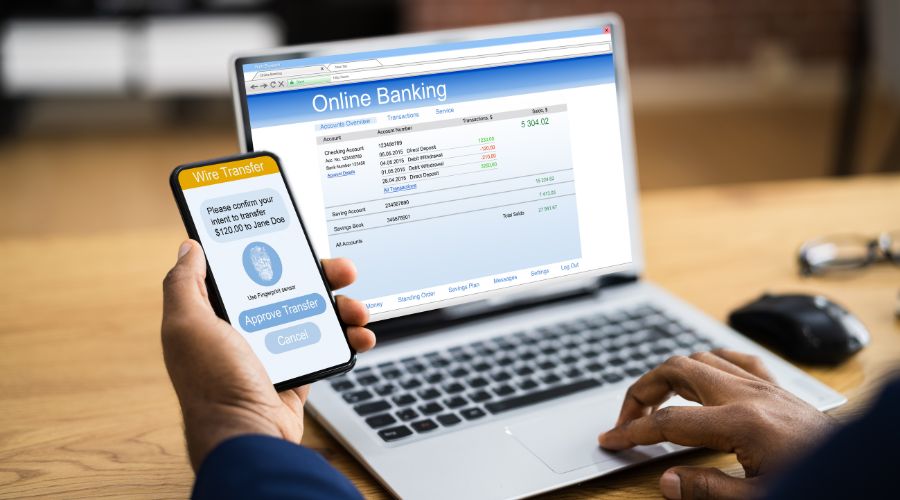 Person using online banking on phone and laptop.