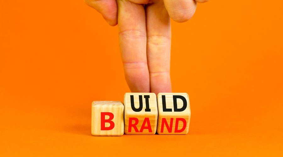 Blocks spelling 'Build Brand' with fingers walking.