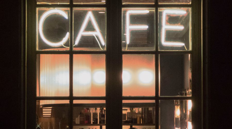 Neon sign on cafe window glowing at night.