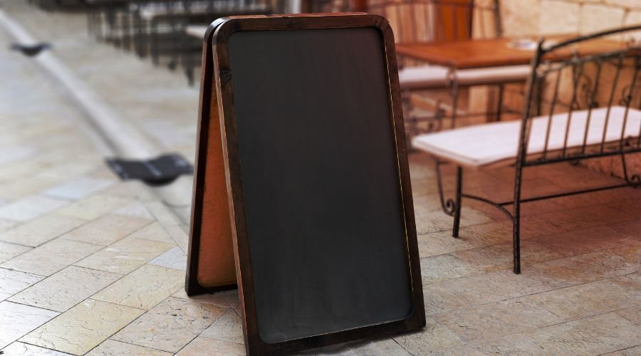 Empty chalkboard sign on outdoor cafe patio