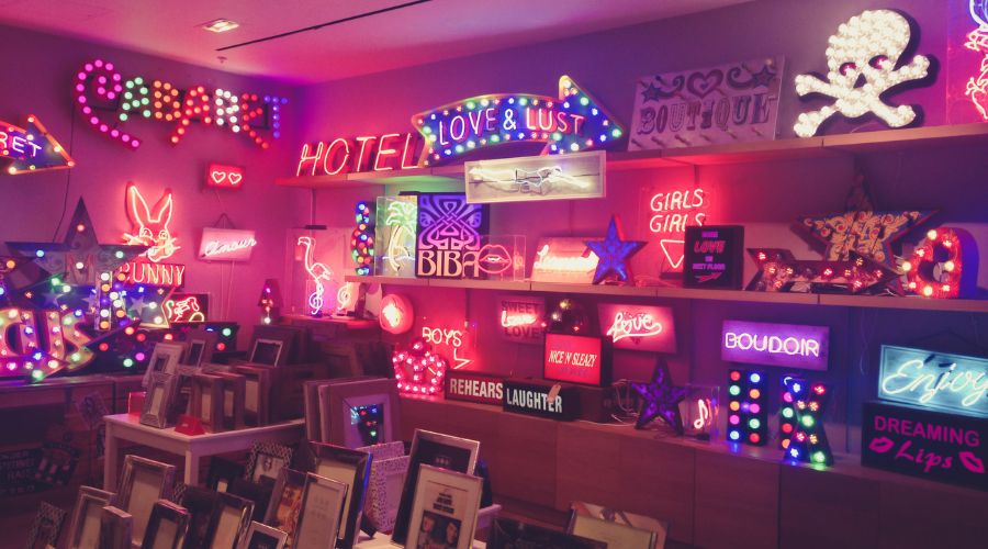 Colorful neon signs on a decorated wall display.