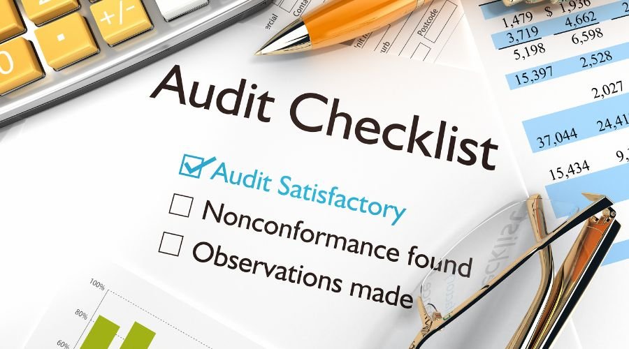 Audit checklist with glasses and pen on desk.