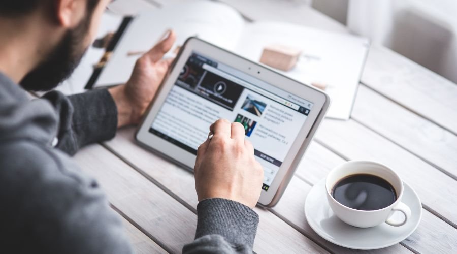 Person reading tablet with coffee on table