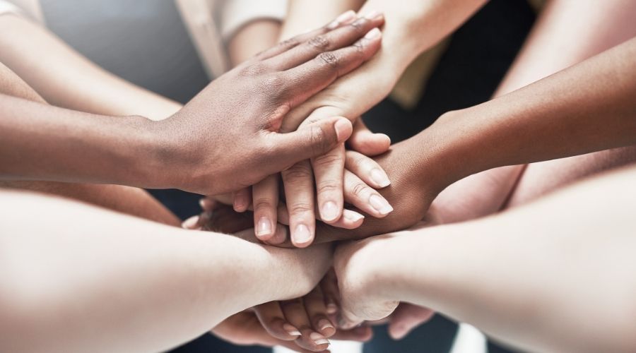 Diverse hands stacked in teamwork unity.
