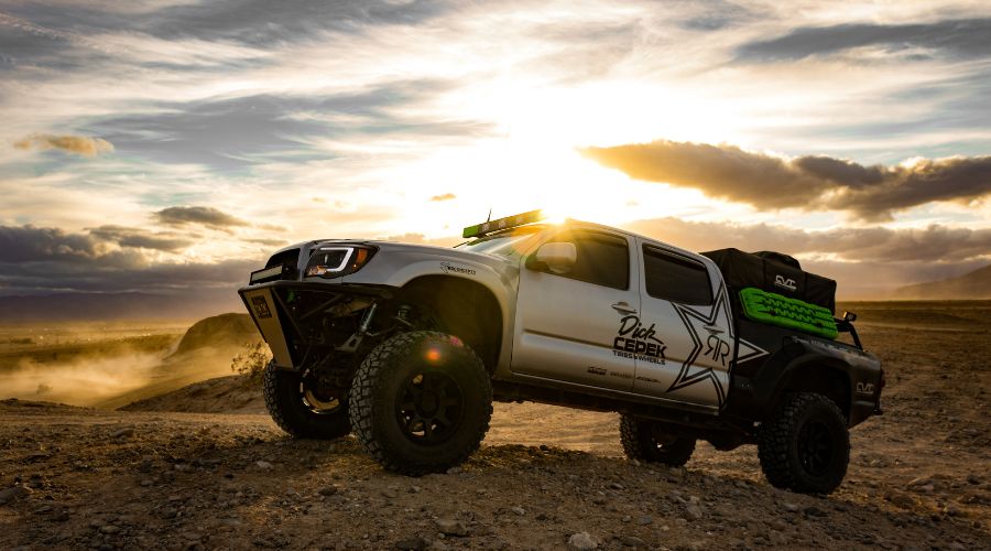 Off-road truck against sunset on rugged terrain.