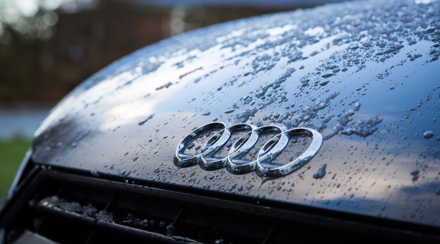 Close-up of raindrops on Audi car hood.