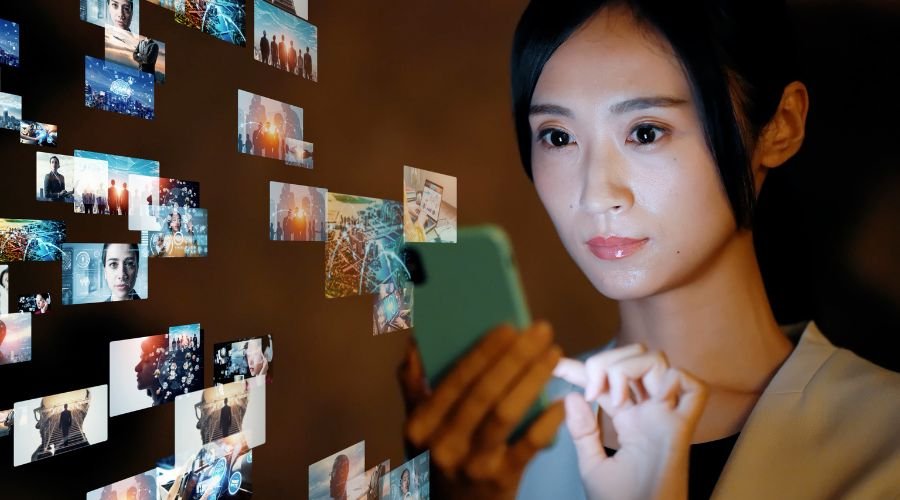 Woman using smartphone with digital media projections.