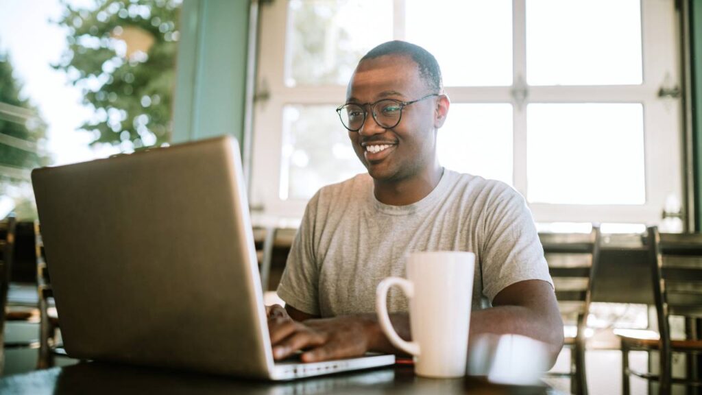 Smiling person working on laptop with coffee mug