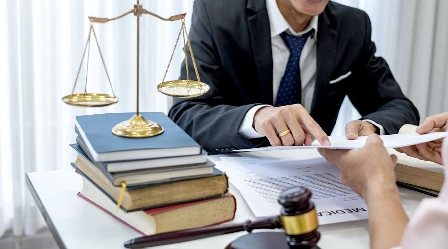 Lawyer discussing documents with client, scales and gavel present.