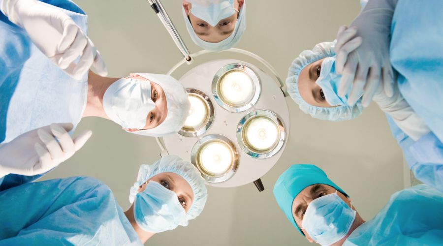 Surgeons operate under bright lights in operating room.