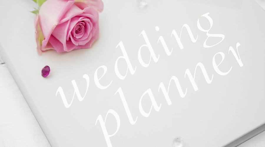 Pink rose and wedding planner text on white paper.