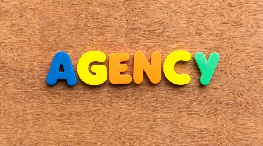 Colorful letters spelling 'agency' on wood background.