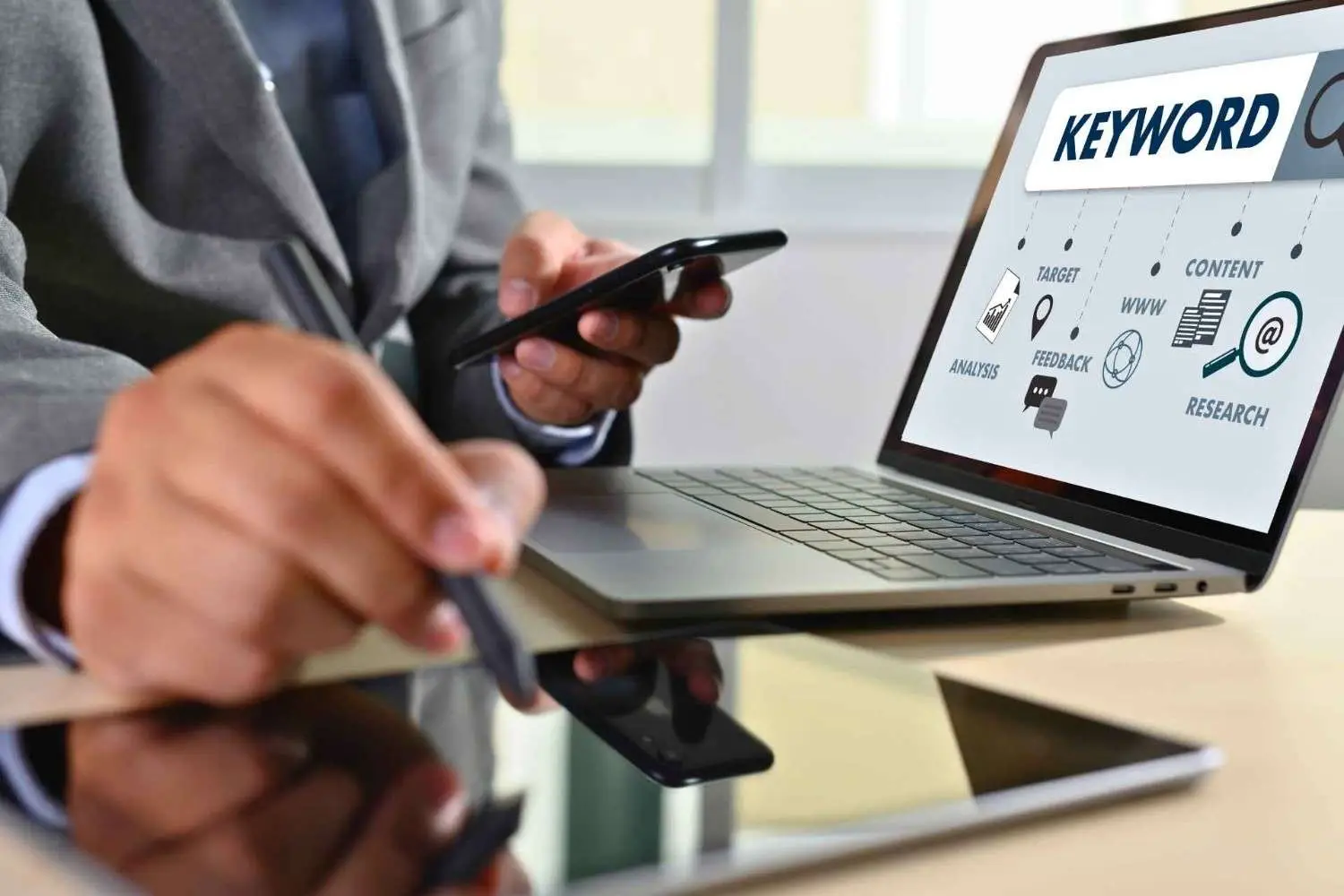 Business professional performing keyword research Australia using a laptop and mobile phone.