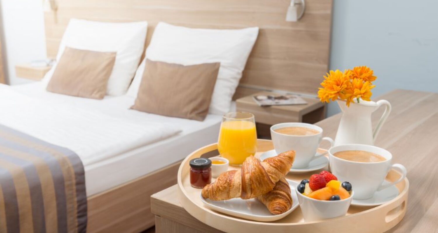 Breakfast tray in cozy hotel room setting.