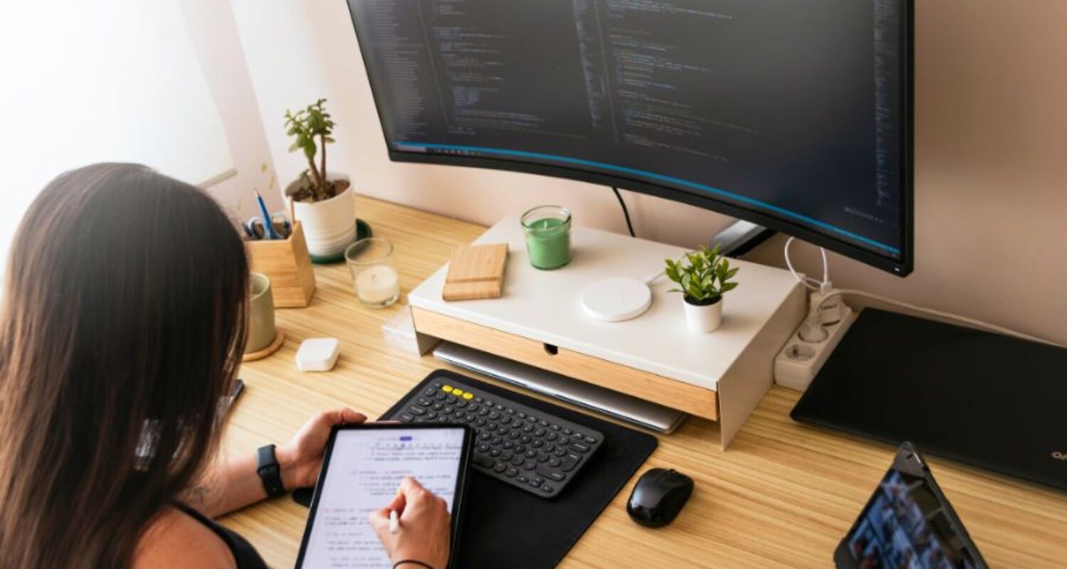 Person working with tablet and computer monitor.