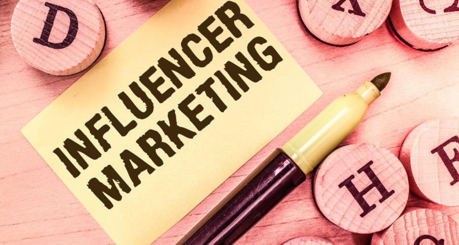 Influencer marketing concept with pen and wooden blocks.