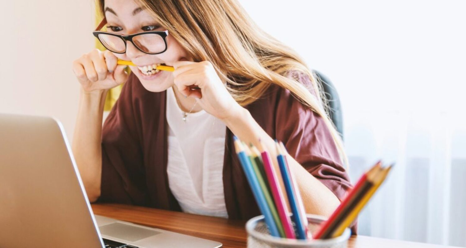 Stressed woman with laptop chewing pencil