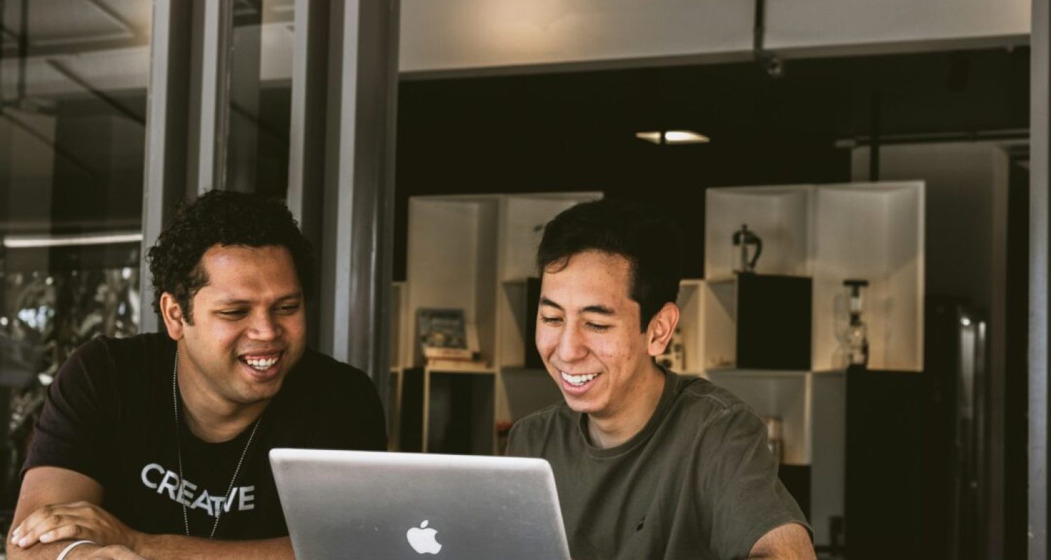 Two men smiling at a laptop