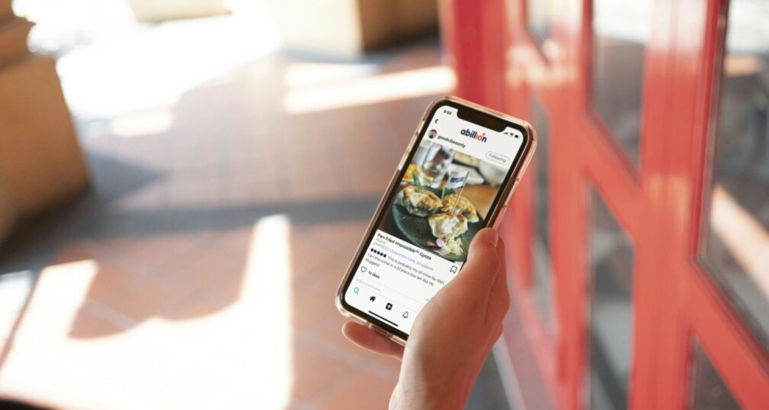 Person holding phone displaying food photo.