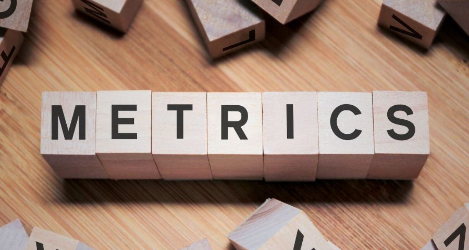 Wooden blocks spell 'Metrics' on table.