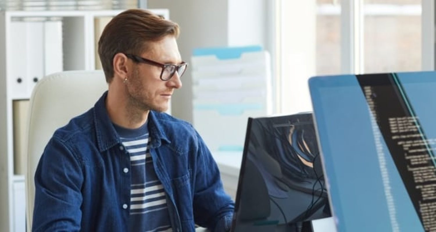 Person coding on computer at desk.